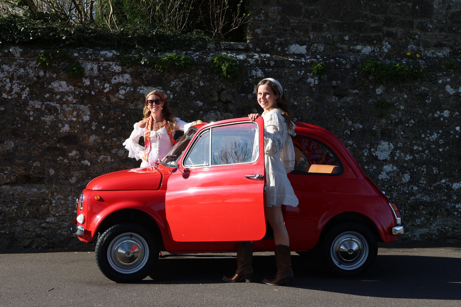 Two friends standing with a bright red classic Fiat 500 — a lifestyle redefined by electric